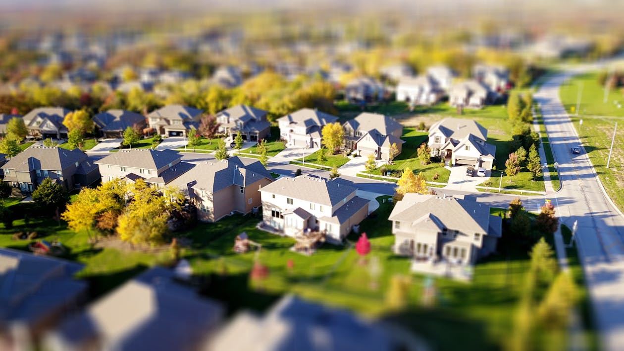 An aerial view captures the layout of a university town, showing the campus buildings integrated with the surrounding residential neighborhoods under a bright, sunny sky.
