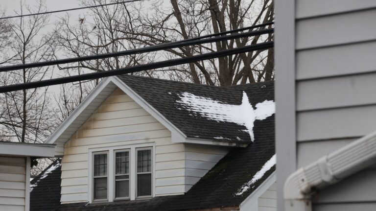Professional home appraiser with a clipboard stands outside a residential house, carefully inspecting the condition of the...