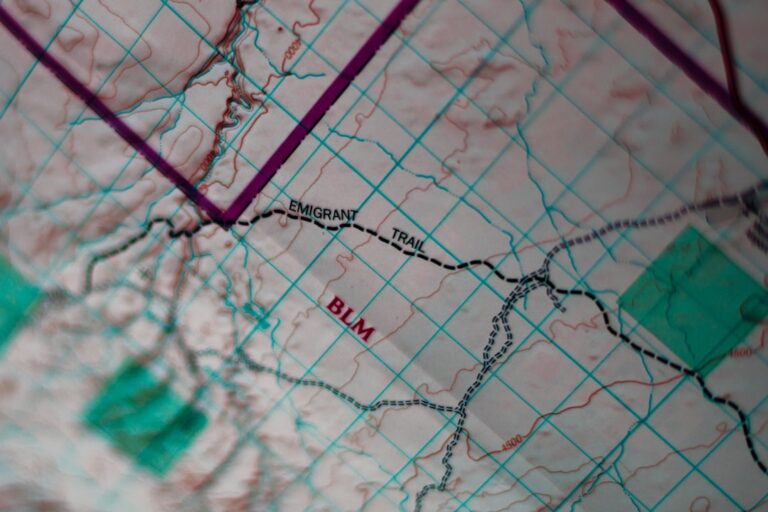 Top-down view of a city map, an open guidebook, a pen, and a notebook laid out on a clean, modern desk, representing profe...